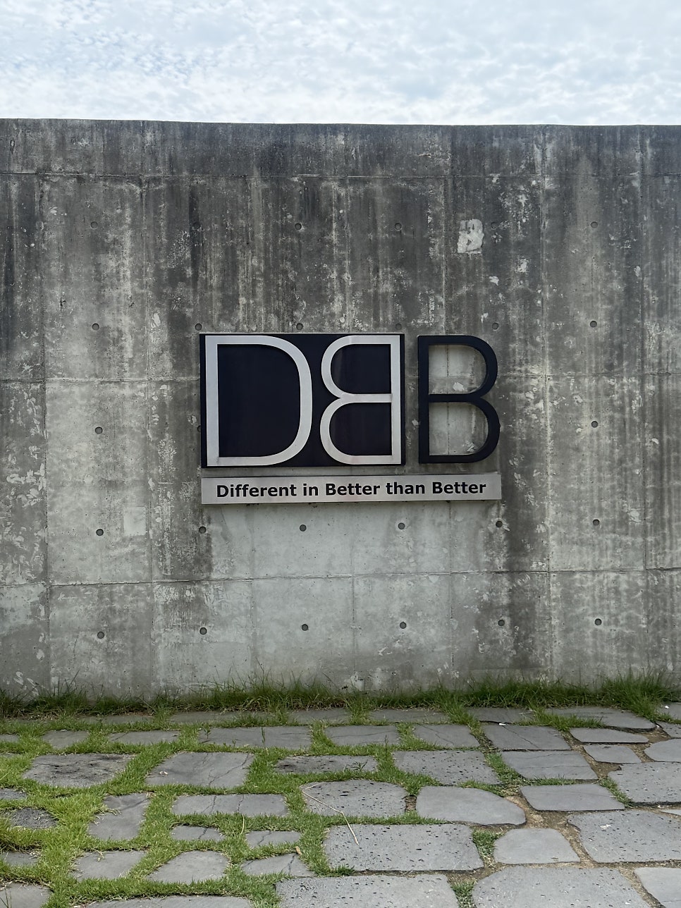 건물 외벽에 붙은 디비비(DBB) 로고. 'Different in Better than Better'라는 문구가 함께 적혀 있습니다.