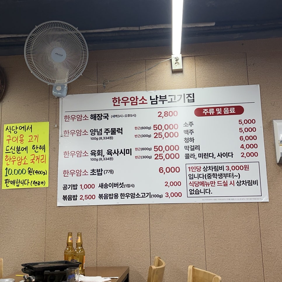 벽에 붙은 메뉴판. 한우암소 해장국 2,800원부터 주물럭, 육회, 초밥, 주류 가격까지 한눈에 볼 수 있습니다.