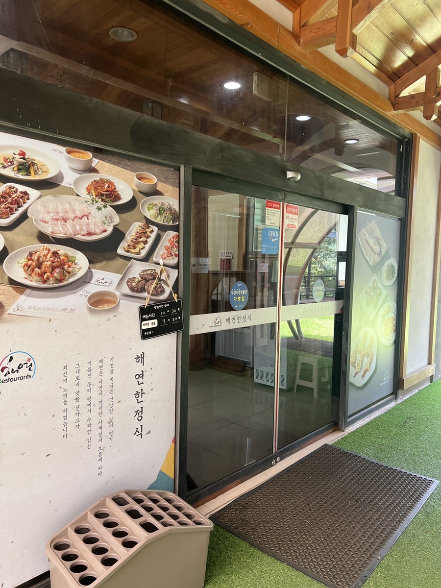 식당 입구. 유리 출입문 너머로 한정식 상차림이 보이고, 간판에는 '해연한정식'이라는 글씨가 명확하게 표기되어 있다.