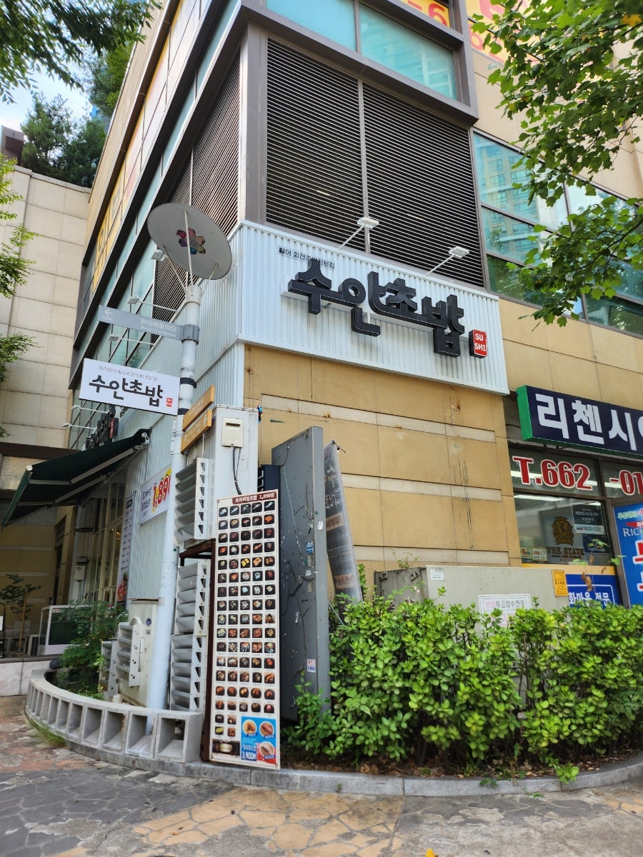 수안초밥 부천중동점 외관. 건물 모서리에 자리해 있고, 벽면에 붙은 메뉴 사진들이 먼저 눈에 들어옵니다.