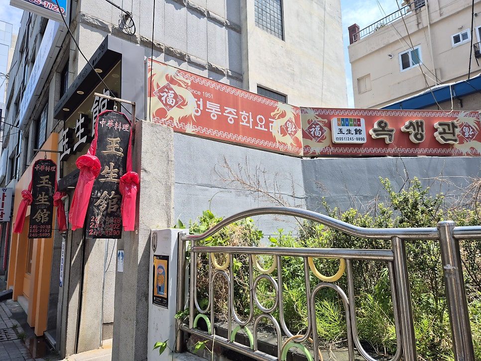 옥생관의 외부 전경과 간판. 중국풍의 장식이 있는 오래된 건물의 면모를 보여줍니다.