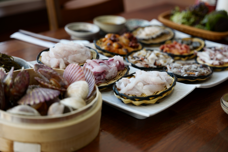 테이블 위에 차려진 모둠 해산물. 회와 조개류가 여러 접시에 나눠 담겨 나옵니다.