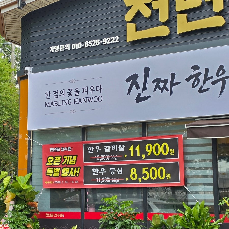 매장 외벽에 붙은 오픈 기념 특별행사 배너. 정상가에서 할인된 이벤트가로 한우를 선보이고 있습니다.