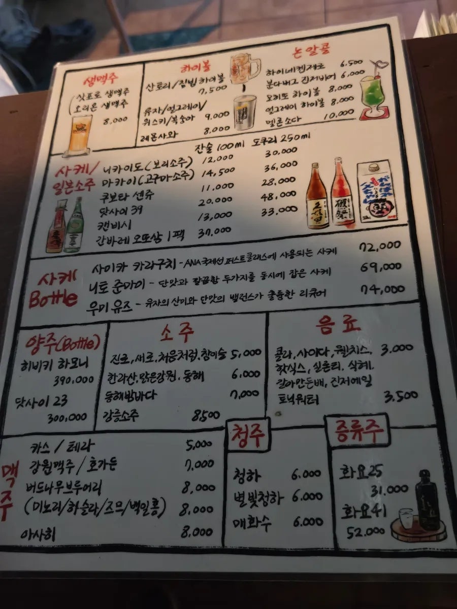 테이블에 놓인 일본 사케 병. 로바다야끼의 음료 선택을 보여줌