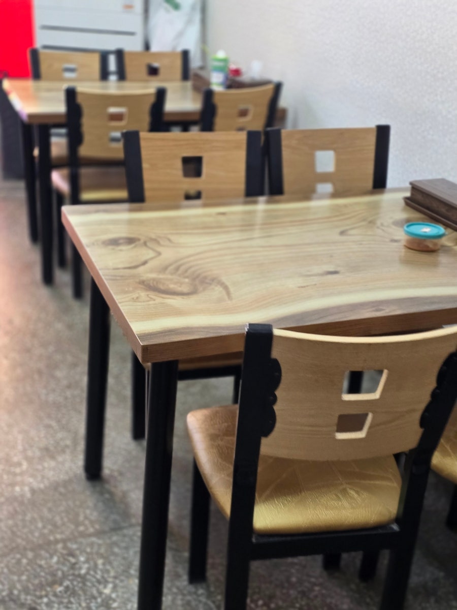 가게 내부 모습. 나무 테이블과 의자가 정렬되어 있고, 정갈하게 정리된 식당입니다.