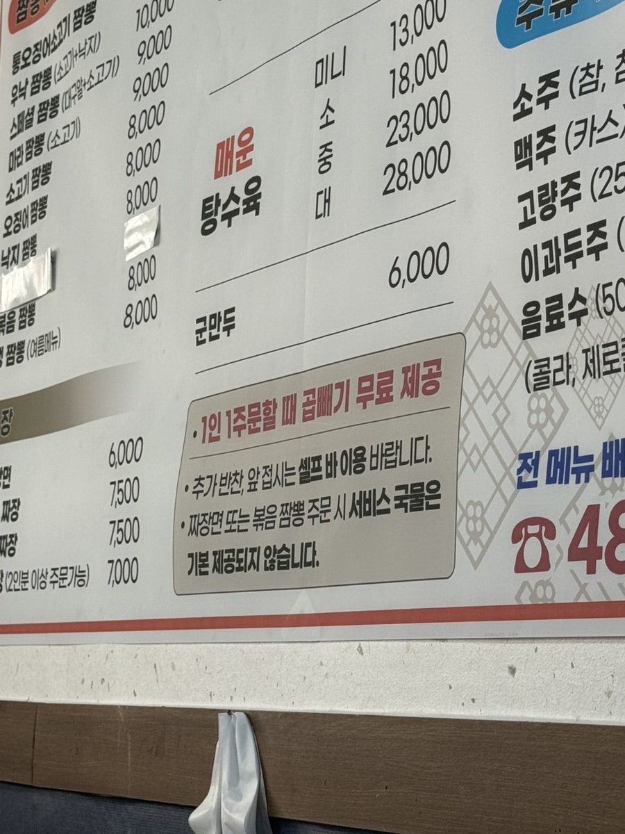 통오징어 소고기 짬뽕의 클로즈업. 붉은 국물에 통통하게 조리된 오징어와 소고기가 선명하게 보입니다.