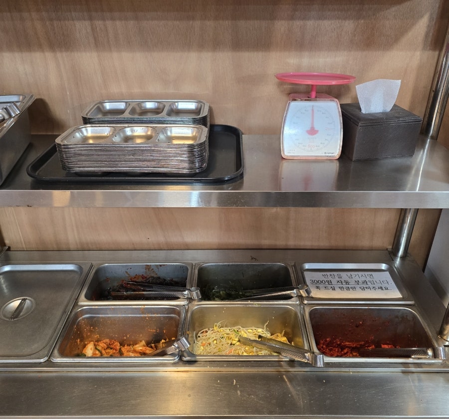셀프 반찬대. 접시와 저울이 놓여 있어 고객이 필요한 만큼 덜어 갈 수 있습니다.