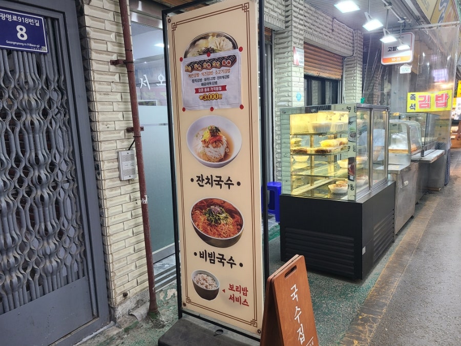매장 입구에 세워진 메뉴 안내판. 잔치국수·비빔국수와 함께 '보리밥 서비스' 문구가 적혀 있습니다.