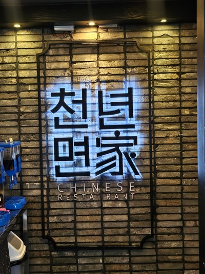 벽돌 벽에 새겨진 '천년면가' 로고. 레드&블랙 톤 인테리어가 인상적입니다