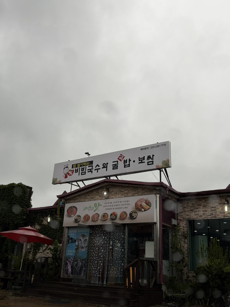 빗속에서 마주한 매장 간판. '밥 말아먹는 비빔국수와 굴밥·보쌈'이라는 문구가 큼직하게 적혀 있습니다
