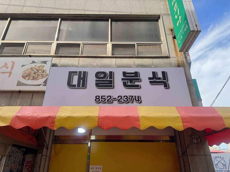 대일분식 간판. 건물 벽면에서 주소 '26-7'을 확인할 수 있고, 출입문 앞에는 정기휴무를 알리는 안내문도 붙어 있습니다.