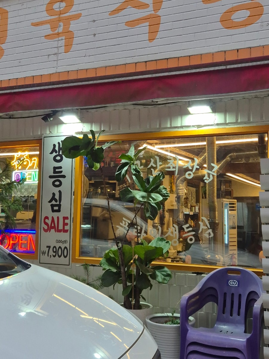 저녁 시간, 조명이 켜진 양지정육식당 입구. '생등심 SALE' 안내판과 화분이 소박한 분위기를 냅니다.
