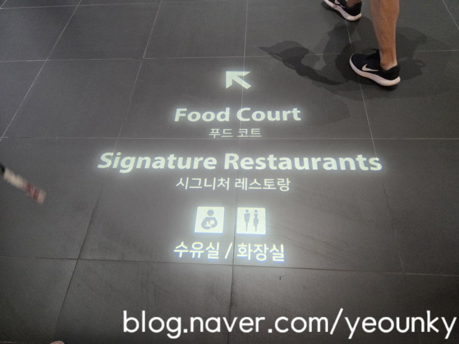바닥에 비치는 안내 표시. 푸드코트와 시그니처 레스토랑 방향을 알려줍니다.