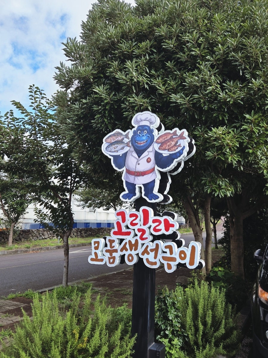 가게 앞 마스코트 조형물. 고릴라 셰프가 생선 두 마리를 든 모습입니다.