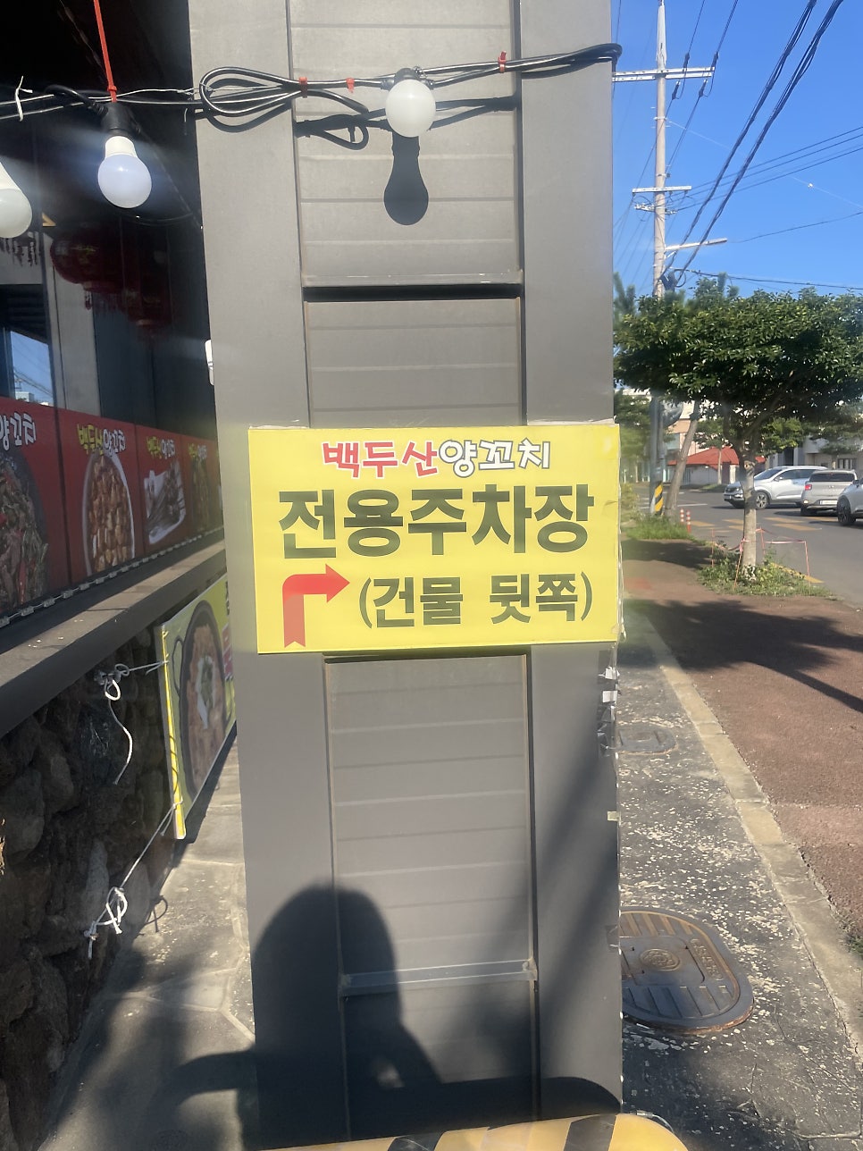 건물 왼편 기둥에 붙은 전용주차장 안내판. 화살표를 따라가면 뒤편 주차장이 나옵니다.