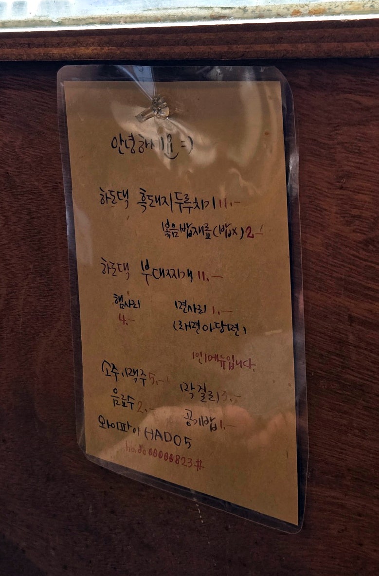 벽에 붙은 손글씨 메뉴판. 두루치기 외에 부대찌개도 있고, 사리나 볶음밥 재료를 추가할 수 있습니다.
