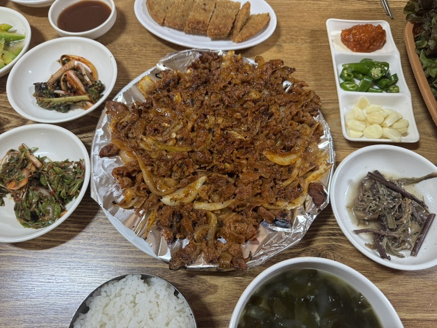 이 날 상에 오른 돼지석쇠구이와 곁들이 반찬들. 산채나물, 멸치볶음 같은 밑반찬에 쌈장·청양고추·마늘, 밥과 미역국까지 한 상 가득 차려집니다.