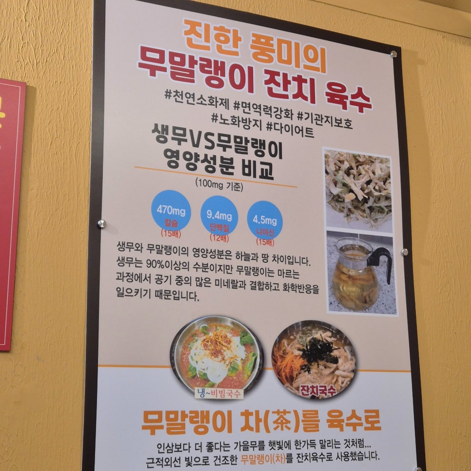 매장 벽에 붙은 무말랭이 잔치육수 설명판. 비빔국수·잔치국수 사진도 함께 있습니다.