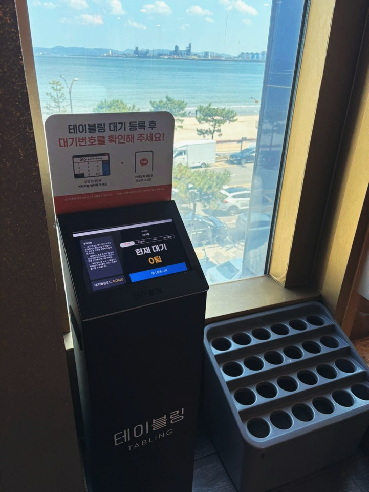 3층 입구의 테이블링 대기 등록 키오스크와 그 너머로 보이는 바다 전망.