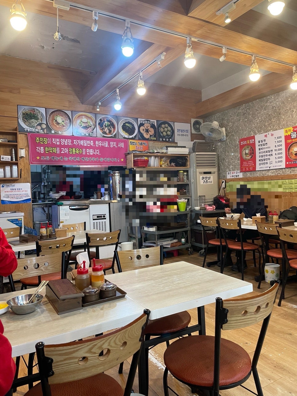 정갈하게 정리된 내부 테이블과 벽에 붙은 메뉴판. 1층 테이블 외에 2층에도 좌석이 있습니다.