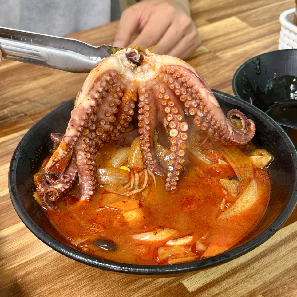 통문어짬뽕. 검은색 그릇 위 빨간 국물에 통문어 한 마리가 고스란히 올려져 있습니다.
