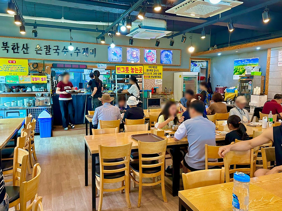 북한산 손칼국수·수제비를 알리는 벽면 안내와 손님들로 북적이는 매장 내부.