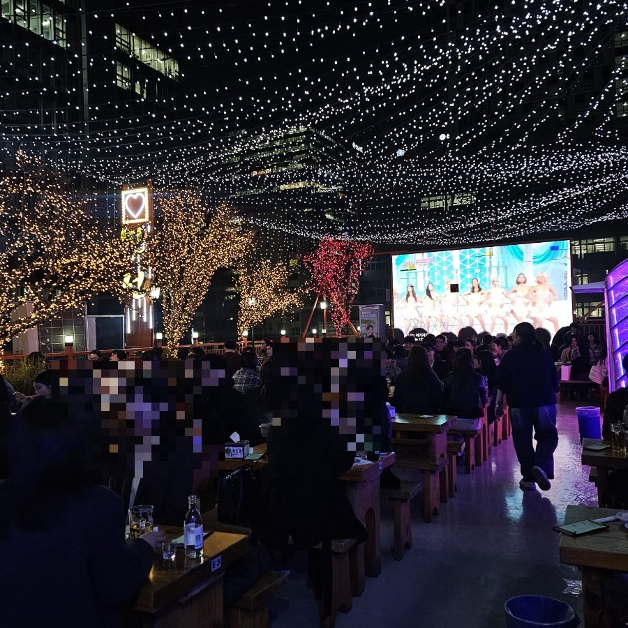 루프탑 야장의 밤하늘. 별 같은 조명과 대형 스크린, 테이블들이 펼쳐져 있습니다.