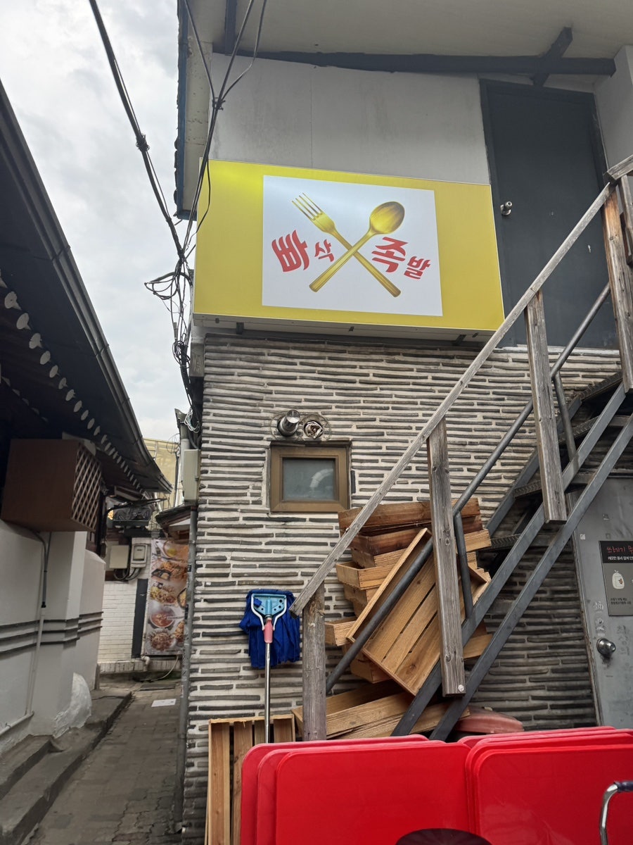 골목에서 올려다본 빠삭족발 간판. 포크와 숟가락이 교차된 로고가 눈에 띕니다.