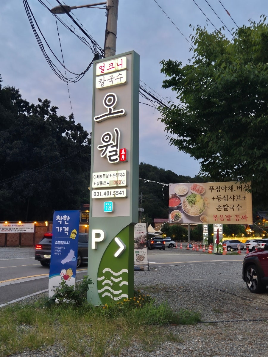 매장 앞 안내 기둥. 전화번호와 착한가격업소 표지, 주차 안내가 함께 있습니다.