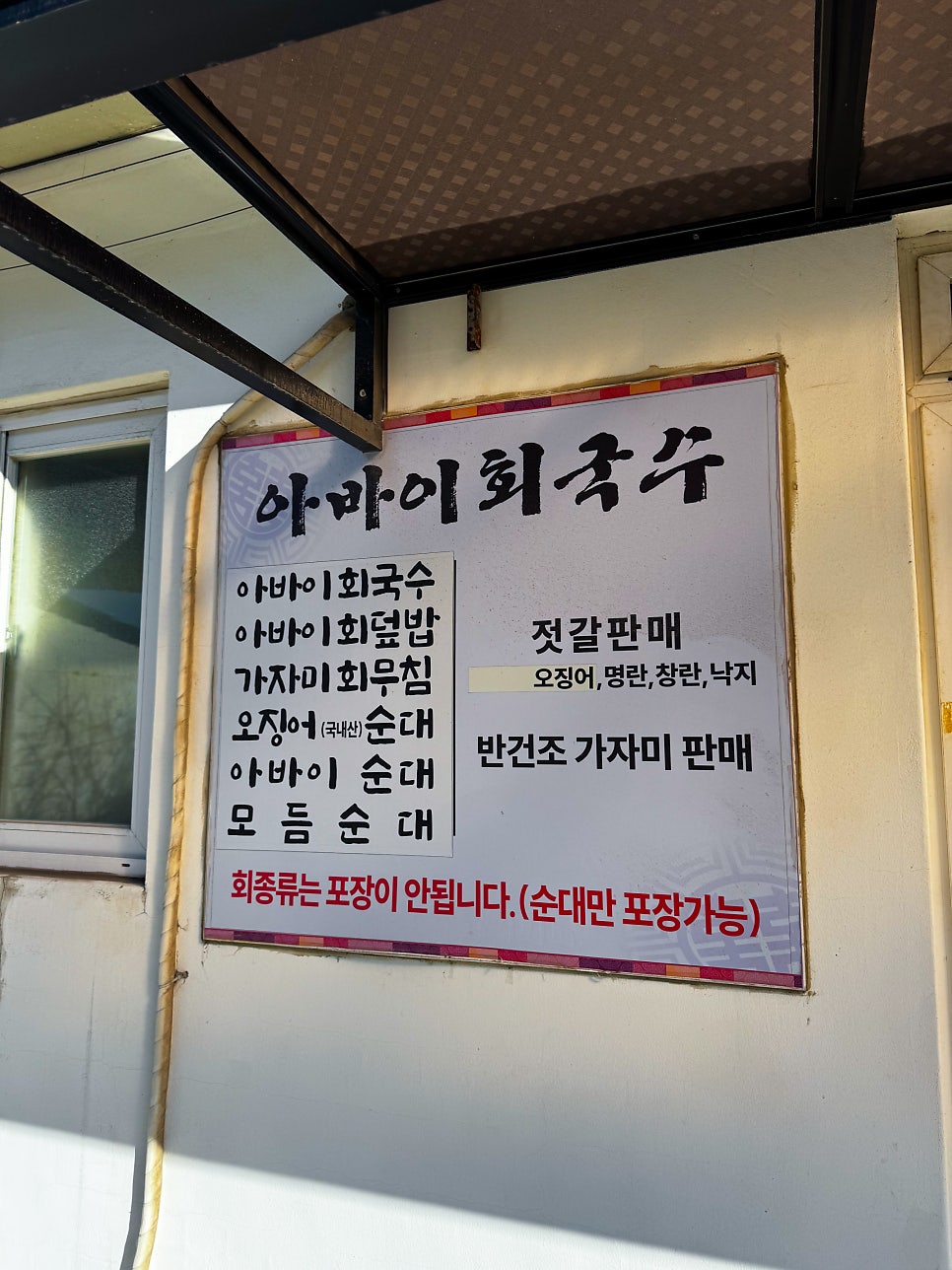 아바이회국수 메뉴 안내판. 회국수·회덮밥·가자미회무침·순대류와 젓갈 판매 품목이 적혀 있고, 회 종류는 포장이 안 된다는 안내도 함께 있습니다.