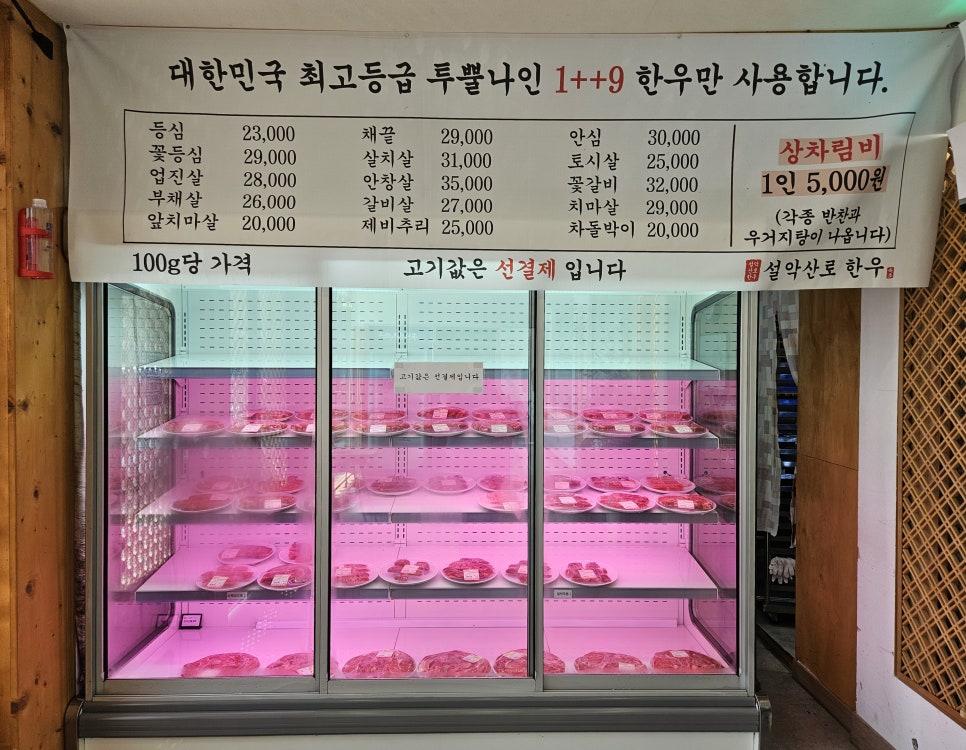 매장 안내판. '대한민국 최고등급 투쁠나인 1++9 한우만 사용합니다'라는 문구와 함께, 1인 상차림비 5,000원에 반찬과 우거지탕이 함께 나온다는 안내가 붙어 있습니다.