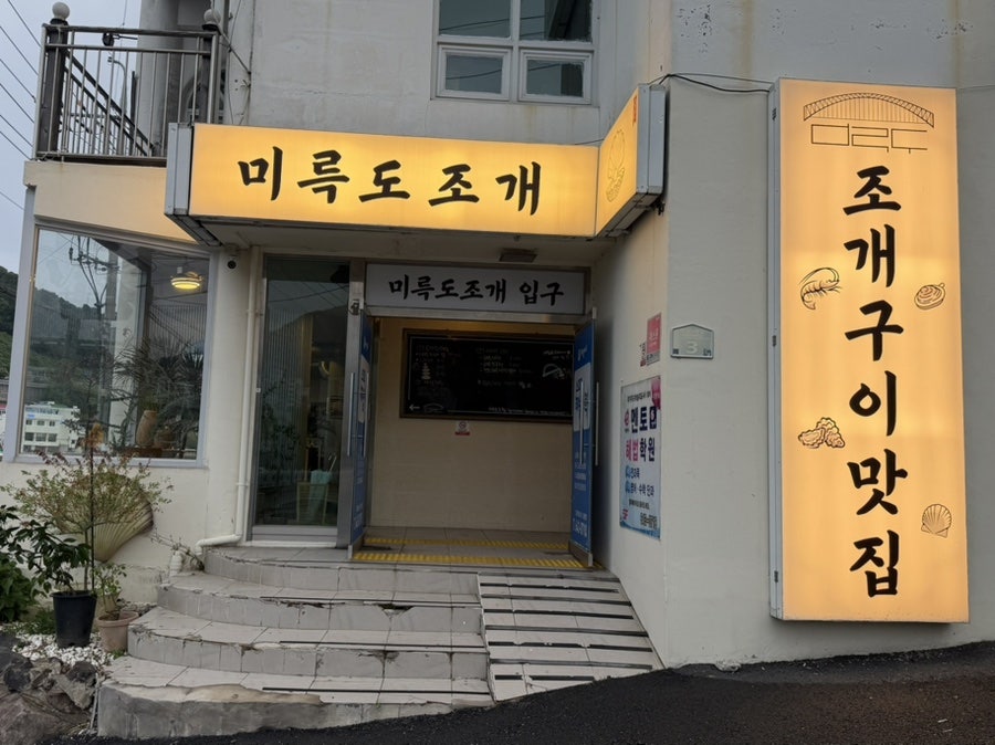 매장 입구의 '조개구이맛집' 간판. 조개 모양 그래픽이 눈에 띕니다.
