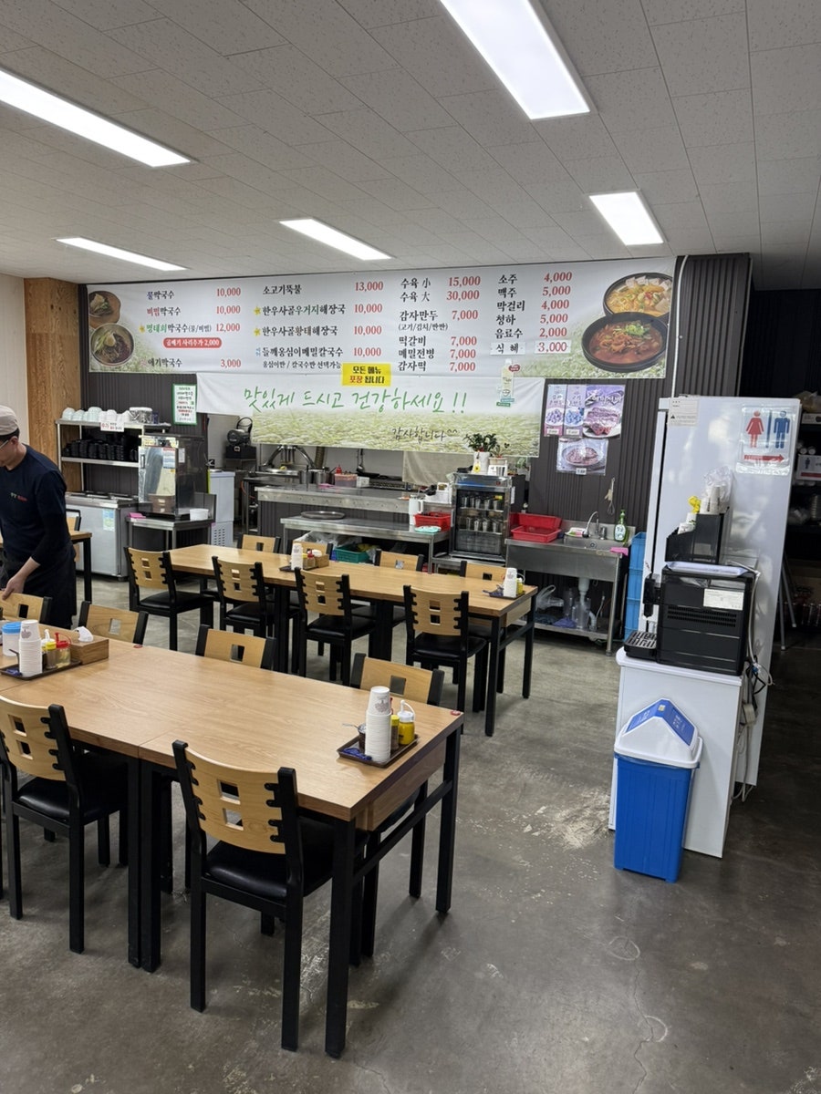 매장 내부 메뉴판. 물막국수·비빔막국수 각 10,000원, 한우사골우거지해장국 10,000원, 수육은 소(小) 15,000원·대(大) 30,000원부터입니다. 좌석도 널찍하고 인테리어가 깔끔합니다.
