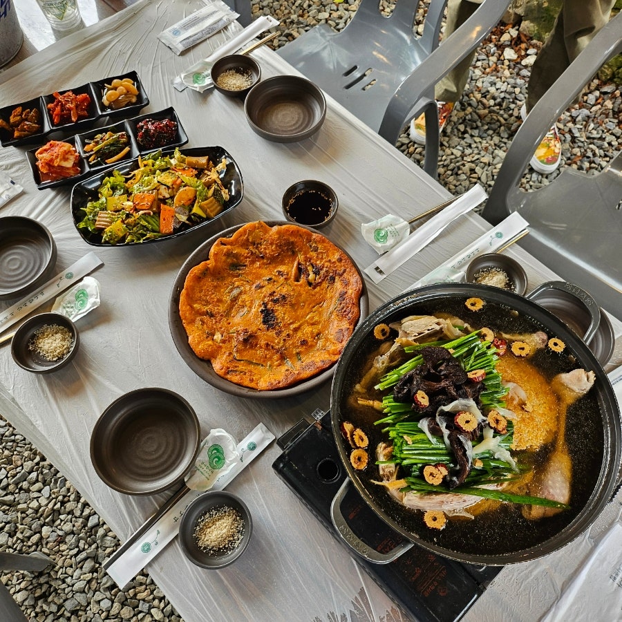 야외 좌석에 차려진 한 상. 백숙과 부침개, 밑반찬이 함께 나옵니다.