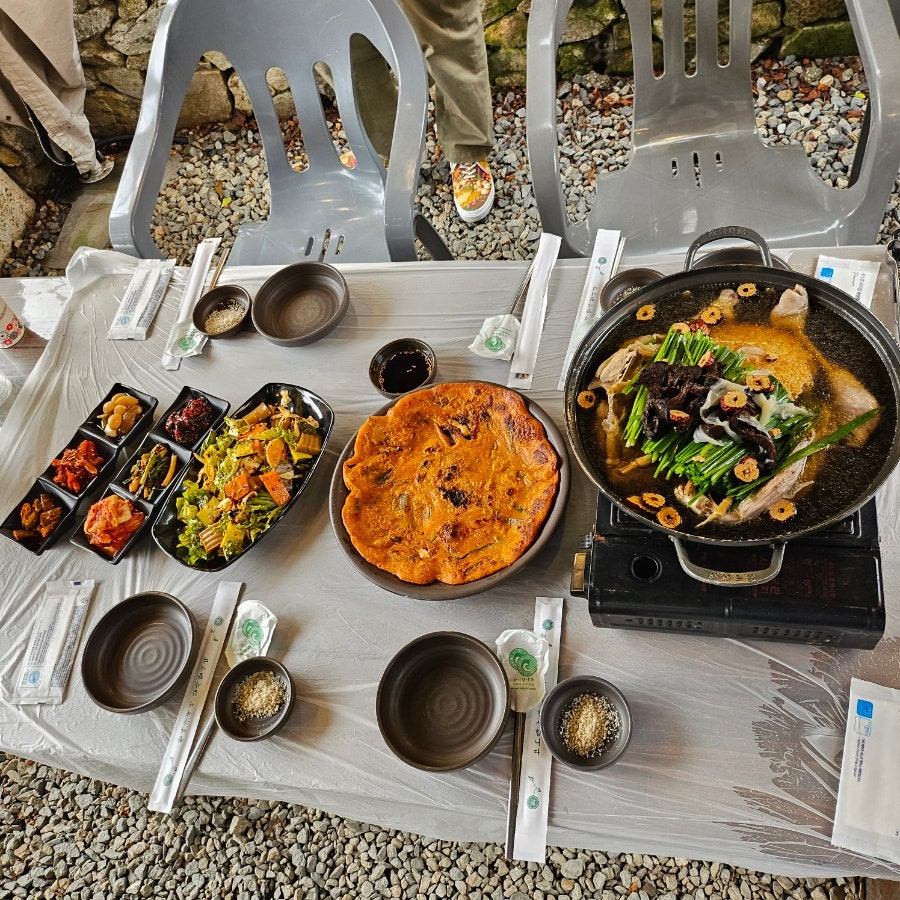 또 다른 야외 좌석에서 바라본 한 상 차림. 돌담을 배경으로 편안한 분위기입니다.