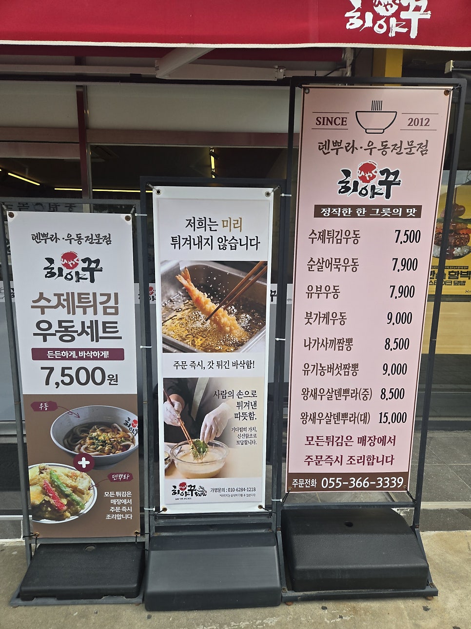 매장 앞 메뉴 스탠드. 수제튀김우동 세트 7,500원을 비롯해 우동·짬뽕 메뉴 가격이 정리되어 있습니다.