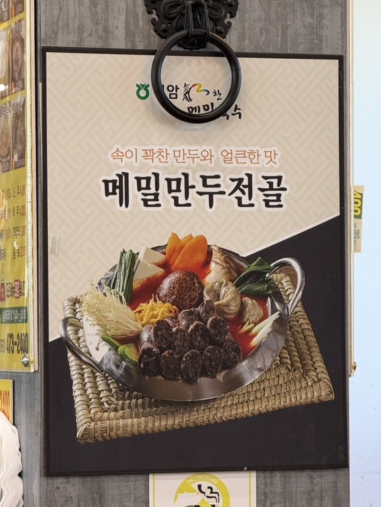 메뉴판 속 메밀만두전골. 속이 꽉 찬 만두와 얼큰한 국물이 특징입니다.